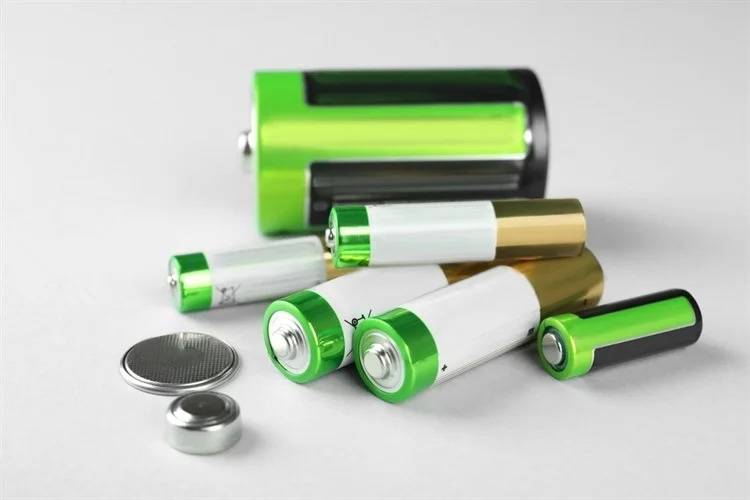 Various AA, AAA, button, and cylindrical batteries with green and white casings
