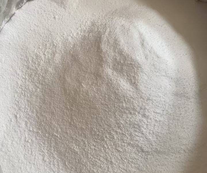 Close-up view of fine white anhydrous zinc chloride powder in a large industrial container