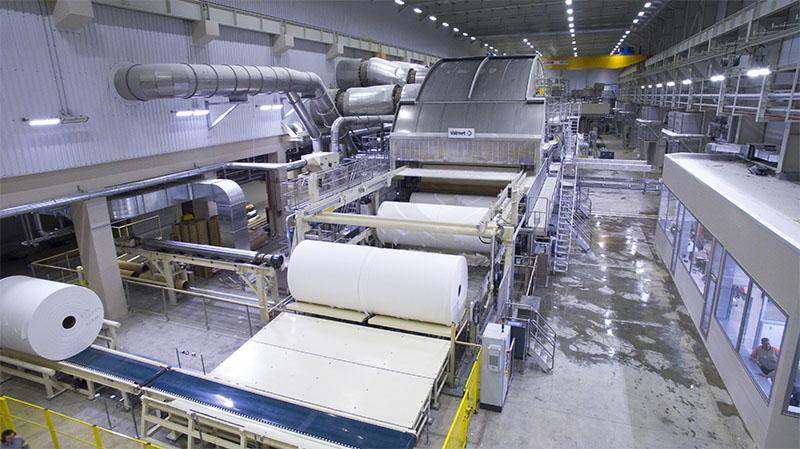 Industrial paper-processing production line with rolls and conveyor equipment inside a factory