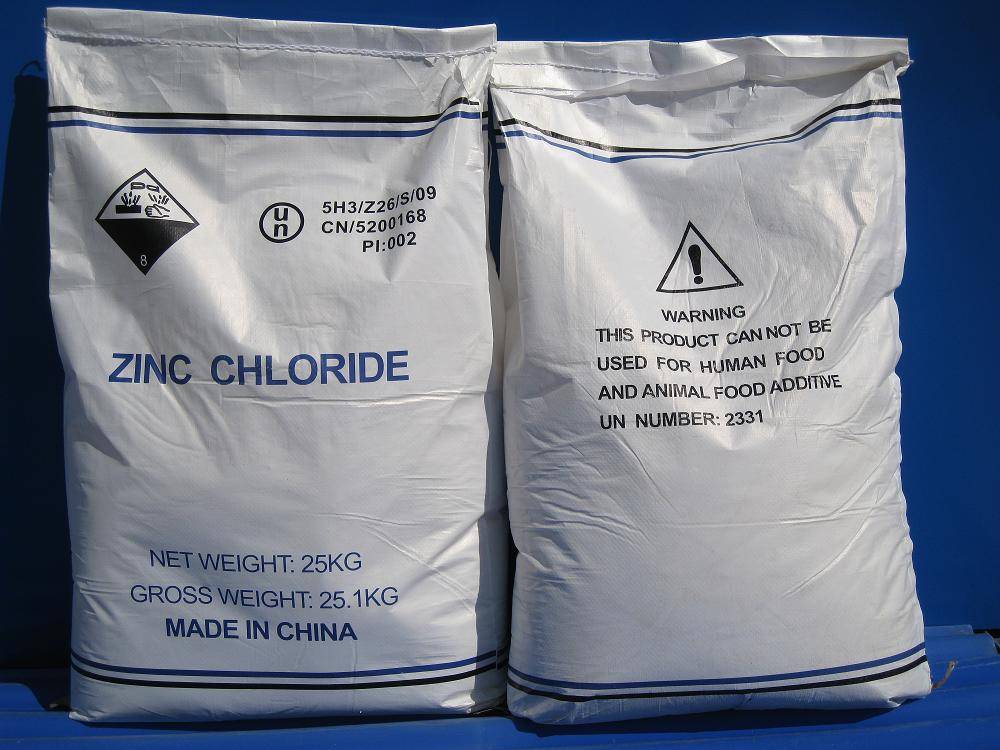 Two sealed industrial bulk bags labeled “Zinc Chloride” on a blue floor